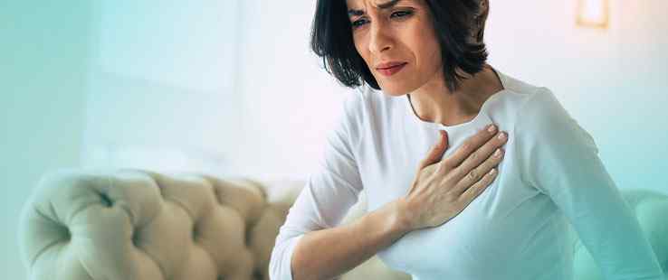 a woman holding her chest while sitting on a couch